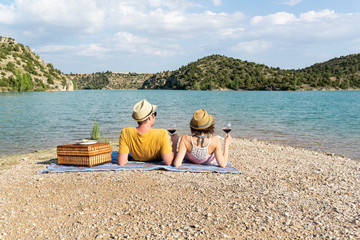 Pareja de enamorados cenando al atardecer a la orilla de un lago