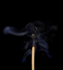 Match off on a black background with smoke