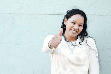 Portrait of beautiful latin teen girl doing thumbs up symbol