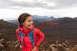 © Maridav - Hiking Asian woman in outdoor volcano landscape walking in Hawaii. Happy hiker on trek with backpack and red rain jacket.