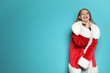 Young woman in Santa costume singing into microphone on color background. Christmas music