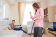 © Aleksei Lazukov - young woman with a mop shows a fist to a man on the couch