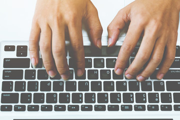 Human hands typing on laptop keyboard