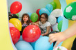 Two cute girls talking while playing with multicolored balloons at kindergarten or at a modern playground