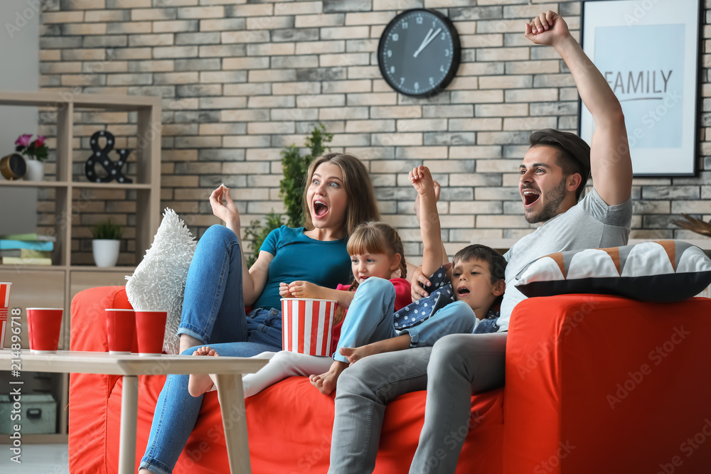 Family watching TV on sofa at home