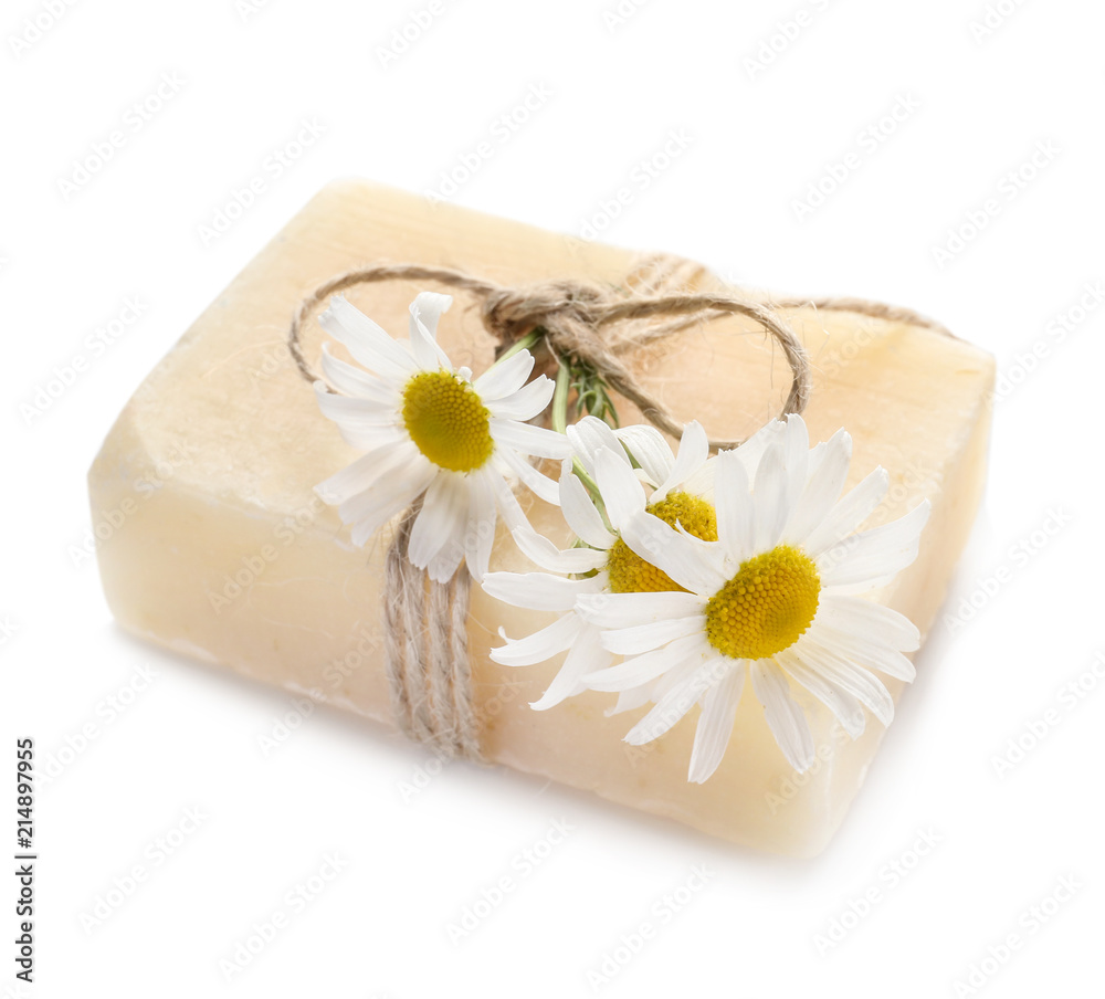 Bar of natural soap with chamomile flowers on white background