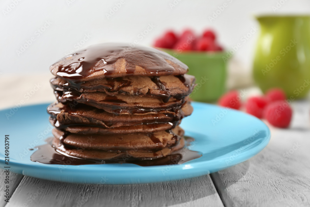 Plate with tasty chocolate pancakes on wooden table, closeup