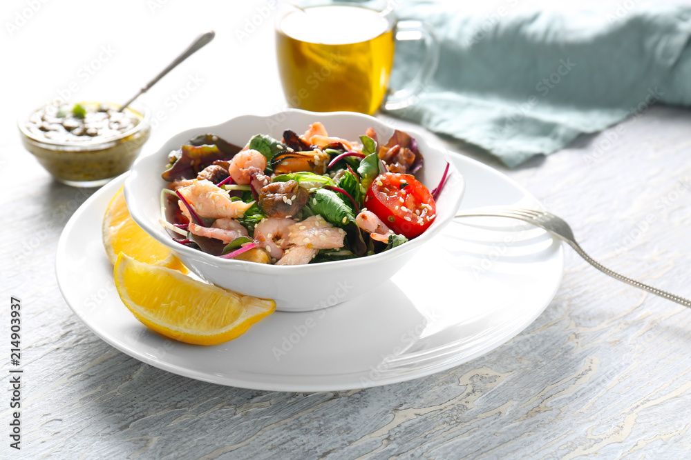 Bowl of delicious vegetable salad with seafood on table
