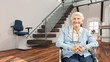 © Robert Kneschke - Seniorin im Rollstuhl vor Treppenlift zu Hause