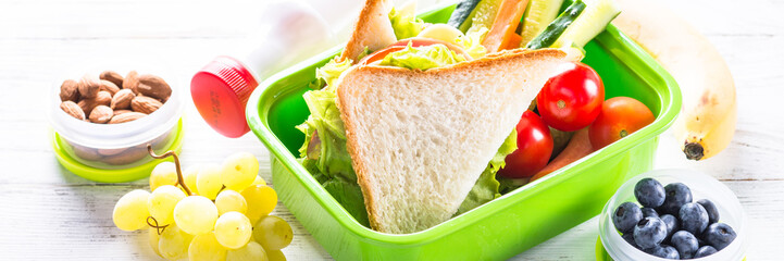 lunch box with sandwich, vegetables, banana, water, nuts and ber