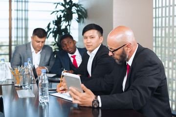 Business people meeting around a boardroom table discussing strategy