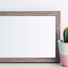 Wooden Frame With Copy Space And Cactus In A Pink Patterned Flowerpot On A Desk