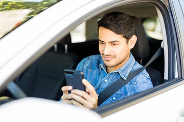 Wall Mural - Young man using mobile phone in a car