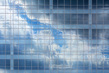 Reflection of the sky and clouds in the Windows of a multi-storey glass building