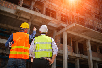 Construction engineers discussion with architects at construction site or building site of highrise building