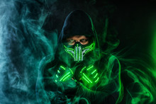 Mysterious Man In Black Wear, Neon Mask And Gloves. Character Pastor Or Wizard In Robe From The Future. Assassin With Strong Face Expression. Fantasy Book Or Computer Game Cover Concept.