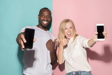 Portrait of a confident casual girl showing blank screen mobile phone and afro man