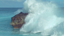 Powerful Turquoise Ocean Wave Splashes Across A Big Rock In The Middle Of Sea