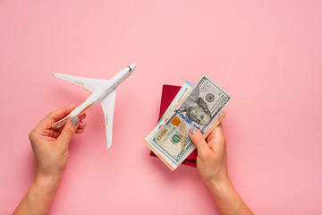 Wall Mural - Plane and money in hand on a pink background.  Travel concept.