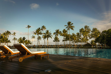 beautiful tropical beach front hotel resort with swimming pool, sun-loungers and palm trees during a