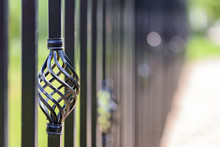Black Decorative Metal Fence, Angular Iron Rods And Curved Upper Part. Close-up Of The Decoration On The Side.