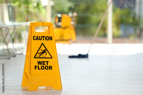 Safety Sign With Phrase Caution Wet Floor And Blurred Mop Bucket
