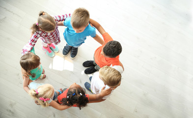 little children making circle with hands around each other indoors, top view. unity concept