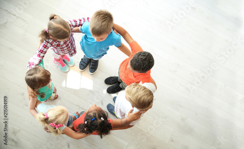 Fotomural Little children making circle with hands around each other indoors, top view