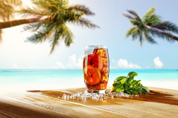 Fresh cold ice tea drink on table and landscape of beach with two palms. 