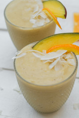 Wall Mural - Close up of Useful breakfast: smoothies of mango, banana and orange on a white table