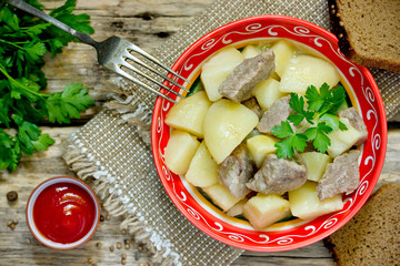 Canvas Print - Potato and pork meat stew in bowl on wooden background top view, rustic food