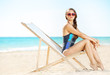 © Alliance - young woman in beachwear on beach sitting in beach chair