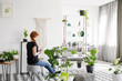 Ginger woman reading a book in a modern living room interior with plants