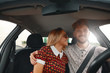 © diignat - Young couple sitting on the front passenger seats and smiling wh