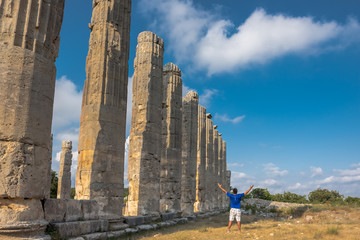 Young man in t-shirt, outdoor with arms spread open enjoying freedom at Zeus temple at Uzuncaburc Ancient city located in Uzuncaburc,Silifke,Mersin,Turkey.