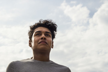 confident latino guy smiling. successful student with sky background