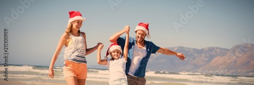 Fotografia Happy family wearing Santa hat while enjoying at beach
