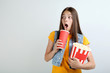 © 5second - Young girl holding bucket with popcorn and paper cup on grey background