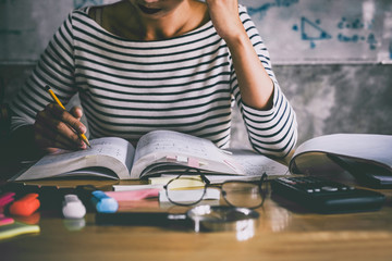 Wall Mural - young student sitting at desk in home studying and reading, doing homework and lesson practice prepa