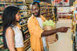 © LIGHTFIELD STUDIOS - african american man with paper bag with food pointing to girlfriend in supermarket