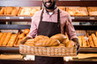 © LIGHTFIELD STUDIOS - cropped image of happy african american male shop assistant in apron holding loaves of bread in hypermarket