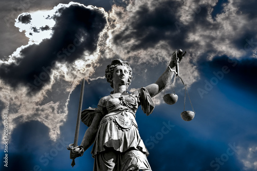 Fotografie, Obraz Die Gerechtigkeitsgöttin Justitia vor einem dramatischen Himmel mit Waagschale i