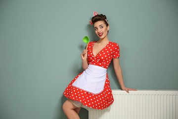 Poster - Funny young housewife with ladle near color wall