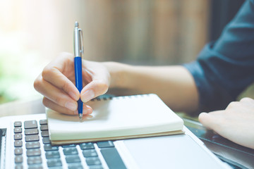 Business woman writing on a notebook.with a pen in the office