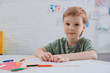 © LIGHTFIELD STUDIOS - portrait of preschooler sitting at table with colorful pencils in classroom