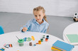 © LIGHTFIELD STUDIOS - portrait of cute child sitting at table with paints and paint brushes