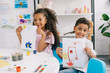 © LIGHTFIELD STUDIOS - portrait of happy african american kids showing pictures at table in classroom