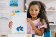 © LIGHTFIELD STUDIOS - portrait of african american kid showing colorful picture in hands while sitting at table in room