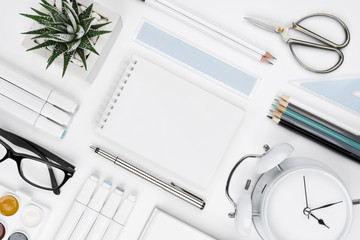 White tabletop with office supplies and blank notebook in center