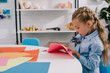 © LIGHTFIELD STUDIOS - side view of focused kid cutting paper with scissors at table